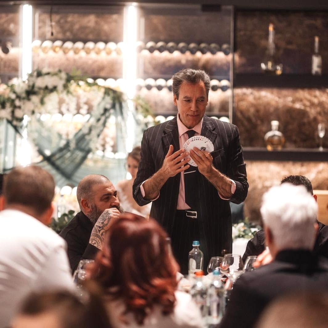 Carlos Vaquera réalisant une expérience de magie de proximité au milieu des invités pendant un repas.