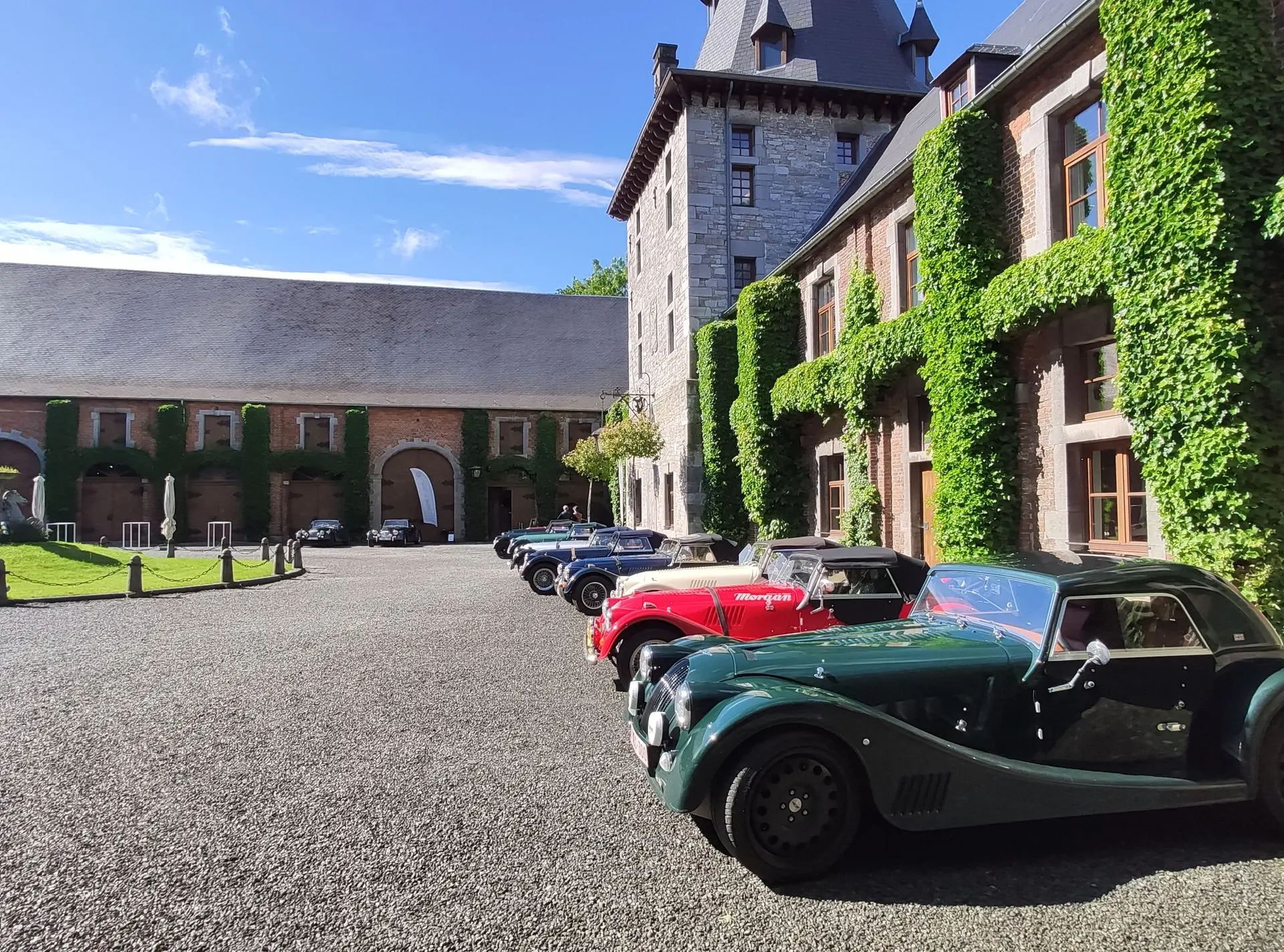 Des voitures anciennes alignées dans la cour pavée d'un château
