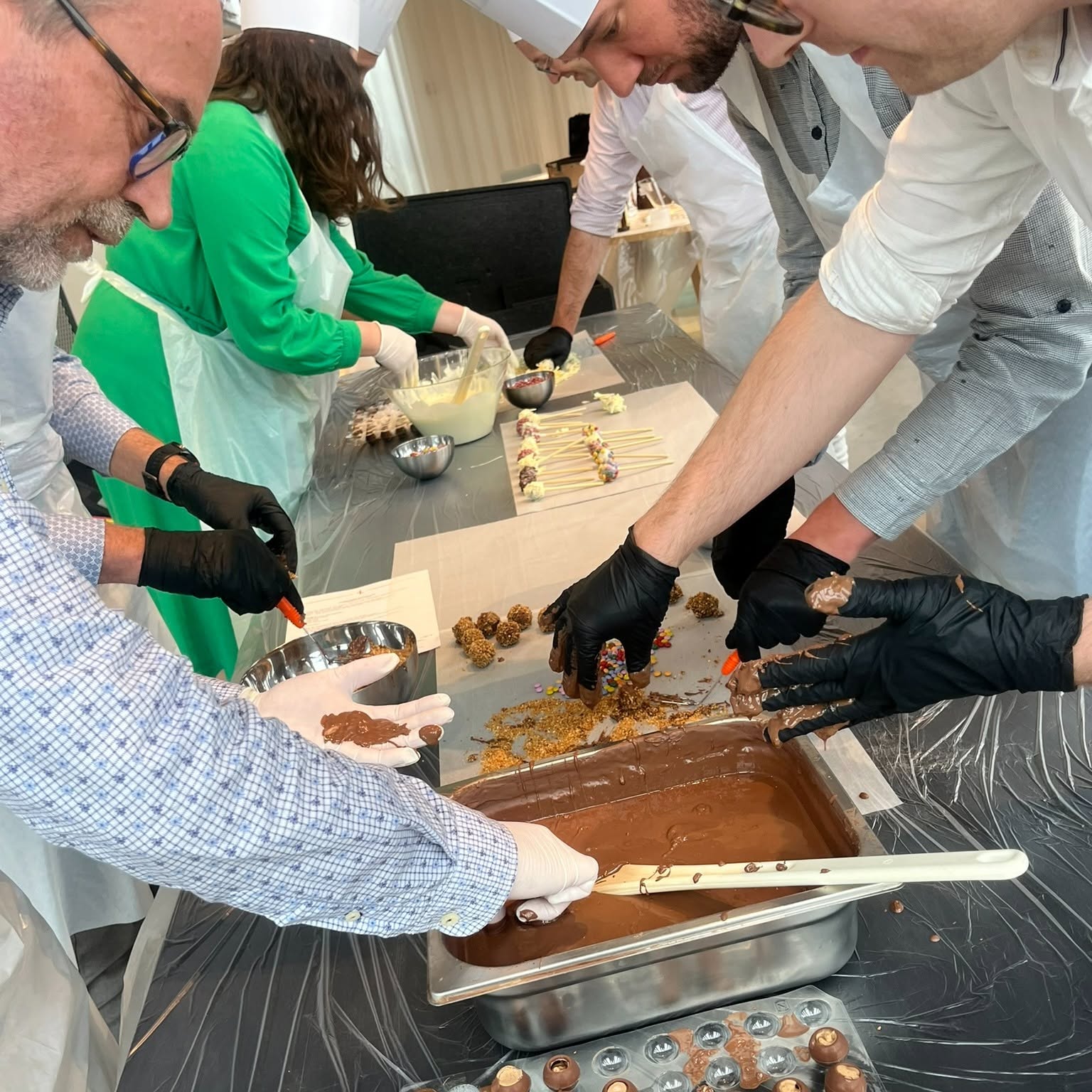 Des collaborateurs façonnent et décorent ensemble des truffes au chocolat pendant un atelier culinaire.