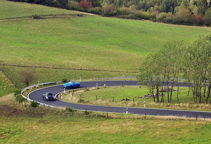 Des voitures anciennes sur une route sinueuse à travers les collines